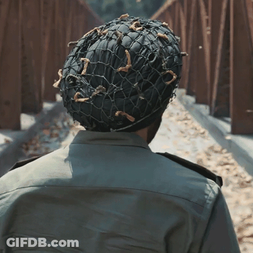 A Man Wearing A Military Uniform And A Helmet With A Net On It GIF