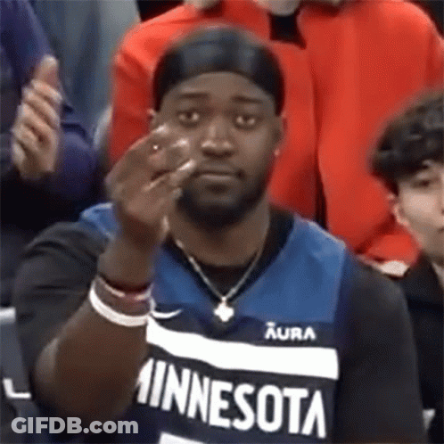 A Man Wearing A Minnesota Jersey Is Giving The Middle Finger While Sitting In The Stands . GIF
