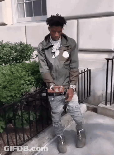 A Man Wearing A Moncler Jacket Stands In Front Of A Fence GIF