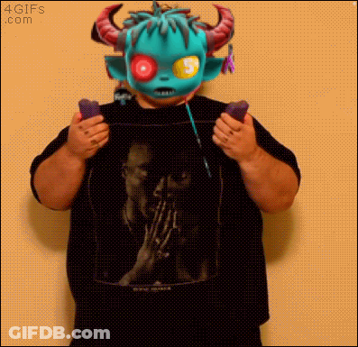 A Man Wearing A Monster Mask Is Holding A Pair Of Remote Controls GIF