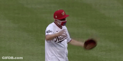 A Man Wearing A Nationals Jersey And A Mask GIF