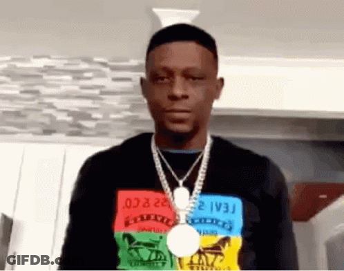 A Man Wearing A Necklace And A Medal Around His Neck Is Standing In A Room . GIF