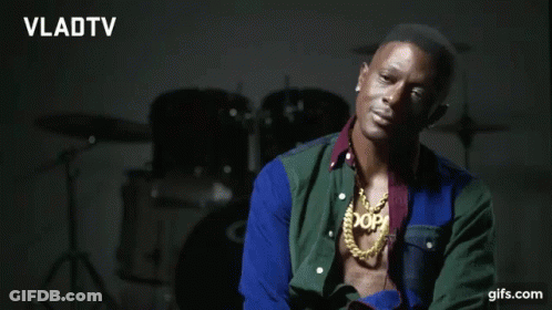 A Man Wearing A Necklace That Says Xop Is Smiling GIF