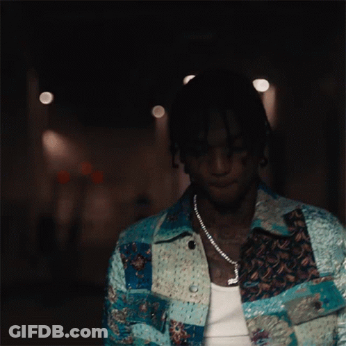 A Man Wearing A Necklace With A Cross On It Looks Down GIF