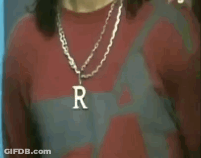 A Man Wearing A Necklace With A Letter R On It . GIF