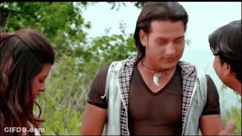 A Man Wearing A Necklace With A Shark Tooth Talks To Two Women GIF