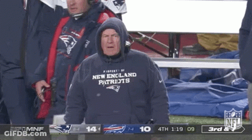 A Man Wearing A New England Patriots Sweatshirt Is Watching A Football Game GIF