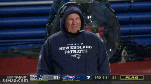 A Man Wearing A New England Patriots Sweatshirt Stands In Front Of A Scoreboard GIF