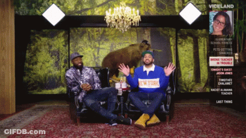 A Man Wearing A New York Shirt Sits Next To Another Man On A Couch GIF