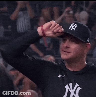 A Man Wearing A New York Yankees Hat Holds Up His Fist GIF