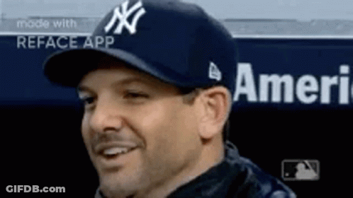 A Man Wearing A New York Yankees Hat Is Smiling In A Dugout . GIF