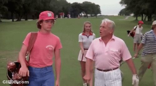A Man Wearing A New York Yankees Hat Is Talking To A Man In A Pink Shirt GIF