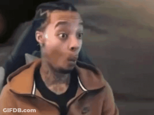 A Man Wearing A Nike Jacket Is Making A Surprised Face While Sitting In A Chair . GIF