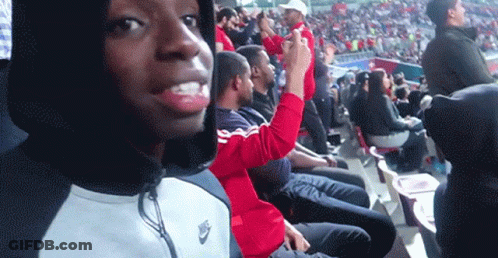 A Man Wearing A Nike Jacket Is Sitting In The Stands GIF