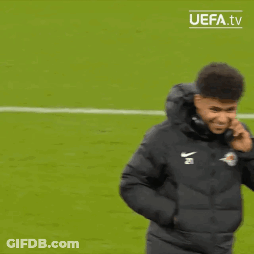 A Man Wearing A Nike Jacket Is Standing On A Soccer Field . GIF