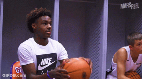 A Man Wearing A Nike Shirt Holds A Basketball In His Hands GIF