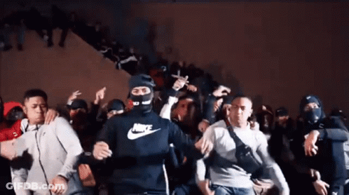 A Man Wearing A Nike Shirt Is Dancing In A Crowd Of People GIF