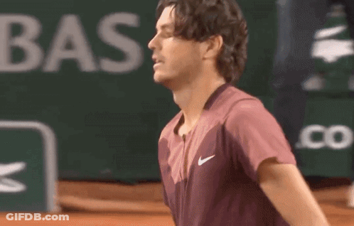A Man Wearing A Nike Shirt Is Standing On A Tennis Court .. GIF