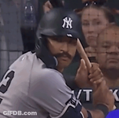 A Man Wearing A Ny Hat Is Swinging His Bat GIF