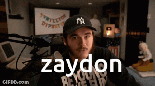 A Man Wearing A Ny Hat Stands In Front Of A Microphone With The Name Zaydon On The Bottom GIF