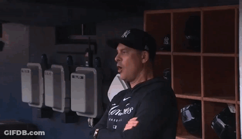 A Man Wearing A Ny Hat Stands Next To Another Man In A Black Shirt GIF
