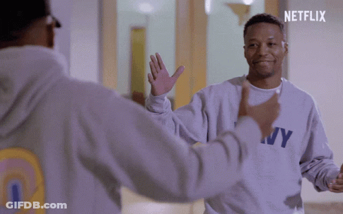 A Man Wearing A Ny Sweatshirt High Fives Another Person GIF
