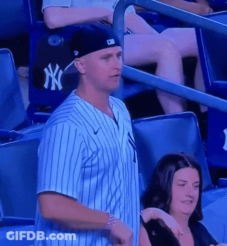 A Man Wearing A Ny Yankees Jersey Stands In A Stadium GIF