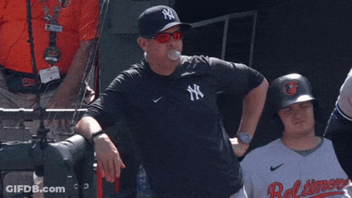 A Man Wearing A Ny Yankees Shirt Stands Next To A Baltimore Player GIF