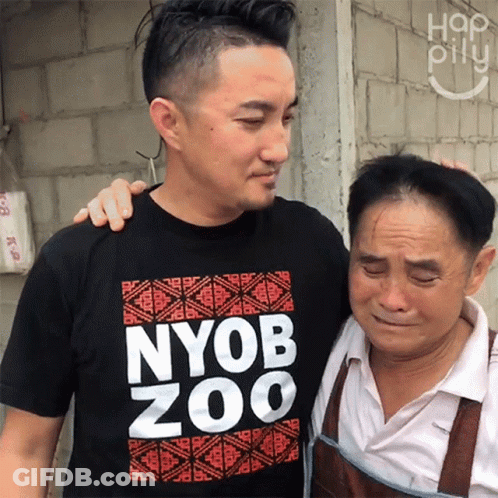 A Man Wearing A Nyob Zoo T-Shirt Hugs Another Man GIF