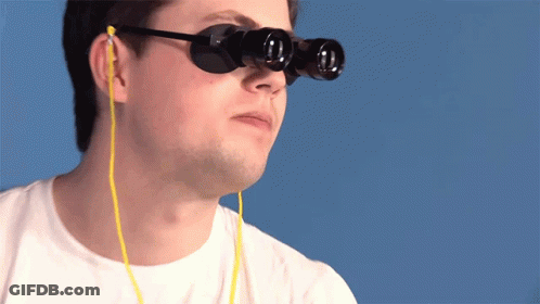A Man Wearing A Pair Of Binoculars With Ear Buds Attached To Them GIF