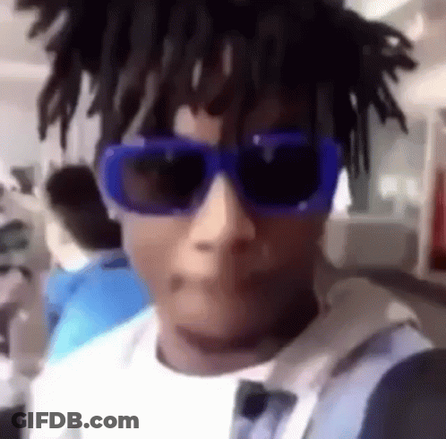 A Man Wearing A Pair Of Blue Sunglasses And Dreadlocks Is Taking A Selfie . GIF