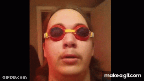 A Man Wearing A Pair Of Red And Yellow Goggles Looks At The Camera . GIF