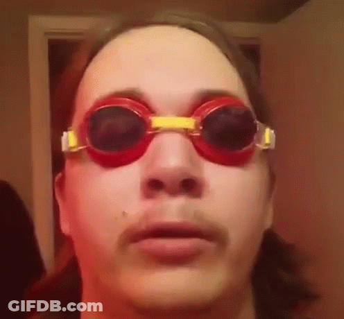 A Man Wearing A Pair Of Red Goggles Looks At The Camera . GIF