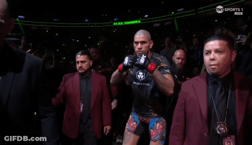 A Man Wearing A Pair Of Ufc Boxing Gloves Stands In A Crowd GIF
