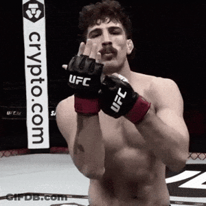 A Man Wearing A Pair Of UFC Gloves Stands In Front Of A Crypto.com Sign GIF