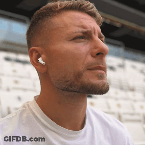 A Man Wearing A Pair Of White Ear Buds Looks To The Side GIF
