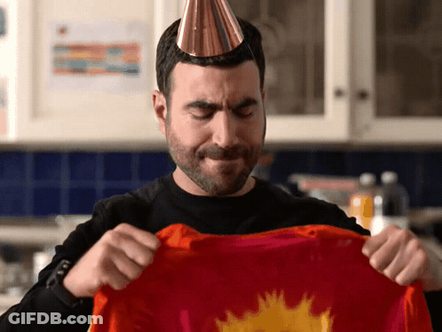 A Man Wearing A Party Hat Holds A Red Shirt GIF
