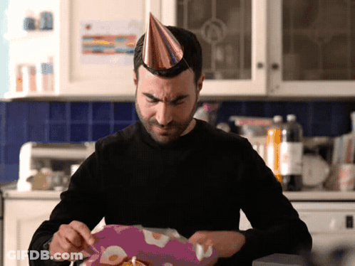 A Man Wearing A Party Hat Opens A Gift Box GIF