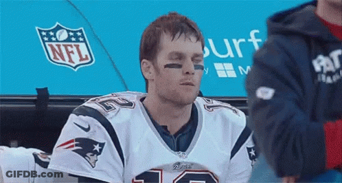 A Man Wearing A Patriots Jersey Is Sitting In A Locker Room With His Eyes Closed . GIF