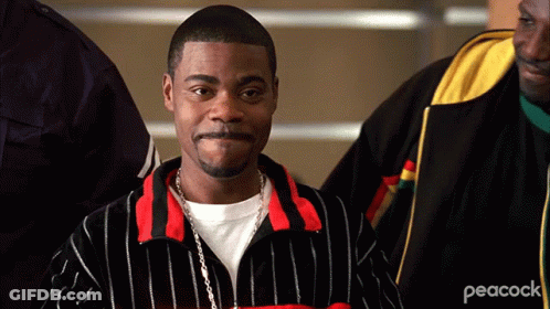 A Man Wearing A Peacock Jacket Is Standing In A Crowd Of People GIF