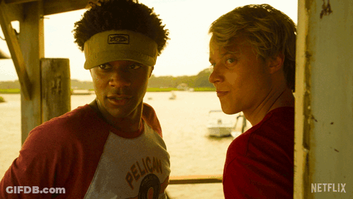A Man Wearing A Pelican Shirt Stands Next To Another Man In A Red Shirt GIF