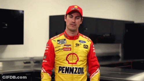 A Man Wearing A Pennzoil Jacket Stands In A Room GIF