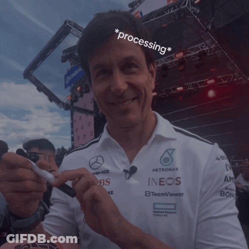 A Man Wearing A Petronas Shirt Holds A Pen In His Hand GIF