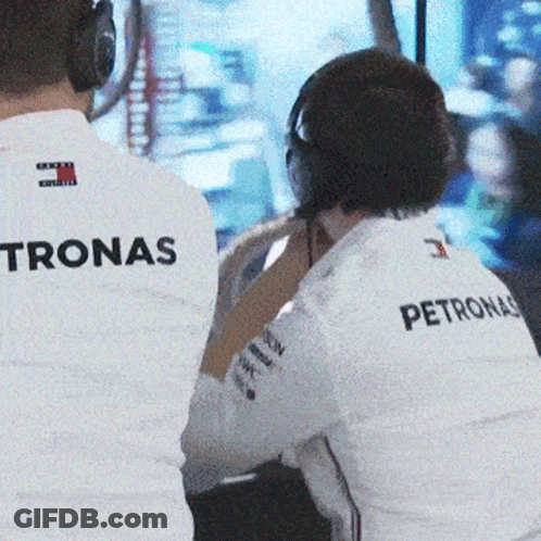 A Man Wearing A Petronas Shirt Sits In Front Of A Monitor GIF