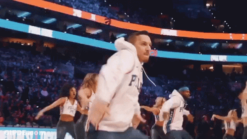 A Man Wearing A Philadelphia 76Ers Jersey Is Dancing With A Group Of Cheerleaders GIF
