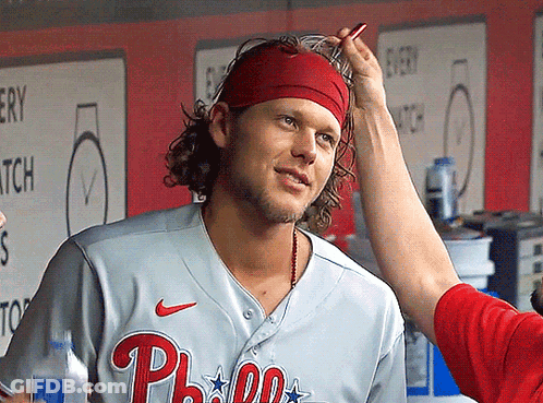 A Man Wearing A Phillies Jersey Is Getting His Hair Brushed GIF