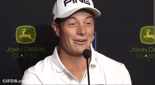 A Man Wearing A Ping Hat Stands In Front Of A John Deere Logo GIF