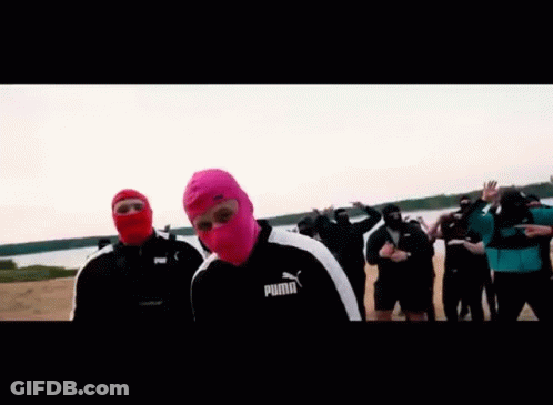 A Man Wearing A Pink Balaclava Is Standing In Front Of A Group Of People . GIF