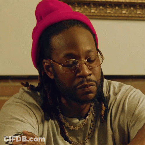 A Man Wearing A Pink Beanie And Glasses Is Looking Down GIF