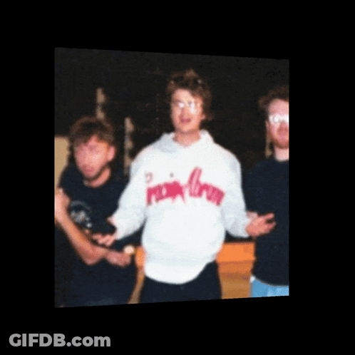 A Man Wearing A Pink Crown Sweatshirt Stands In A Group Of People GIF